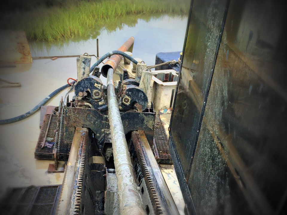 HDD machine with pipe going into marsh